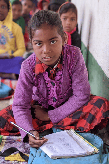 Anika in class writing in her workbook