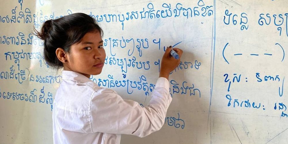 Maly writing on a whiteboard in class